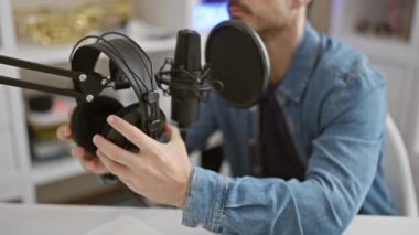 Kulaklıklı İspanyol bir adam bir müzik stüdyosunda mikrofona konuşuyor, bir vokalist kayıt seansını somutlaştırıyor..