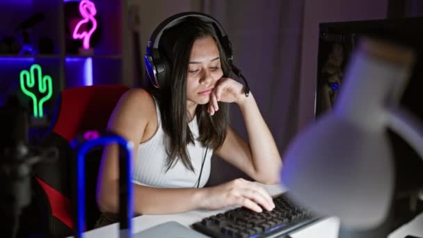 若い美しいヒスパニック女性ストリーマーは ゲームルームでコンピュータを使用して疲れています — ストック動画