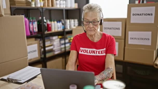 Senior Γκρίζα Μαλλιά Γυναίκα Εθελοντής Χρησιμοποιώντας Φορητό Υπολογιστή Και Ακουστικά — Αρχείο Βίντεο