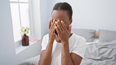 Yorgun bir Afro-Amerikan kadını, stresli ve çok çalışan, yorgun gözlerini yatakta ovuşturan. Baş ağrılarıyla, görme sorunlarıyla ve yorgunlukla boğuşuyor, uykusunu ve acısını dışa vuruyor.
