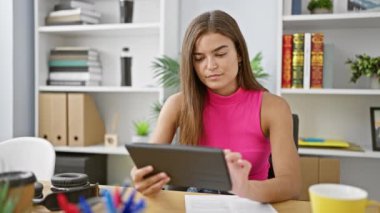 Kendine güvenen genç İspanyol bir kadın, neşeli bir gülümsemesi olan güzel bir işçi ofiste dokunmatik ped kullanarak çalışıyor. İş dünyasındaki başarısının kapalı bir portresi..