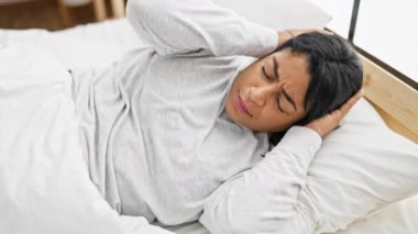 Evde, parlak bir yatak odasında gürültüden rahatsız olmuş, elleri kulaklarıyla kulaklarını kapatan olgun İspanyol kadın..