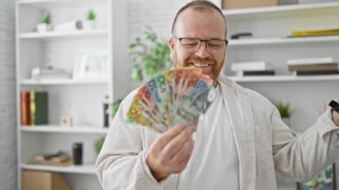 Neşeli beyaz bir adam, yakışıklı bir iş adamı iş yerinde Avustralya dolarlarını havaya fırlatıyor başarı, mutluluk ve ofisin kendine güveni ile köpürüyor.