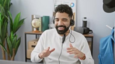 Kulaklıklı neşeli İspanyol bir adam modern ofis ortamında dans etmekten hoşlanıyor..