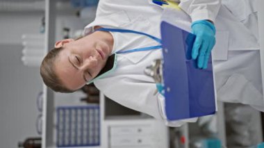 Hevesli genç bilim adamı, sarışın kadın not defterine detaylı notlar alıyor, laboratuvar çalışmalarının ortasında derin telefon konuşmaları yapıyor.