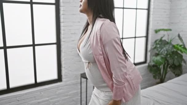若い妊婦 屋内で立っている 穏やかに彼女の一見彼女の寝室の窓に向かって投げます 彼女の腹の上に休む手 — ストック動画