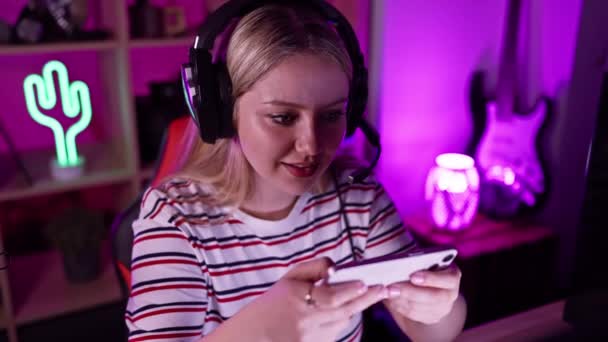 Koncentrerad Ung Kvinna Hörlurar Använder Smartphone Ett Färgglatt Spelrum Natten — Stockvideo