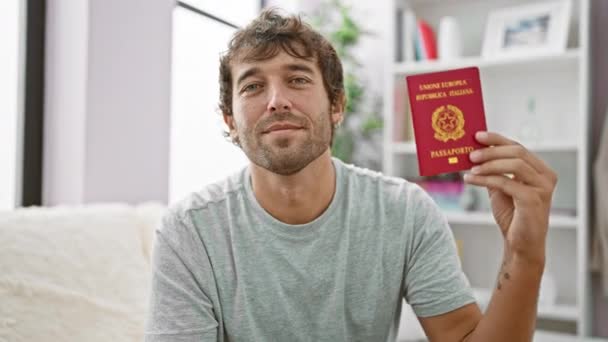 幸せな若者は彼のソファーでエレベーター 自信を持ってイタリアのパスポートを保持し 彼の家の快適さからの休暇の冒険の準備ができて — ストック動画