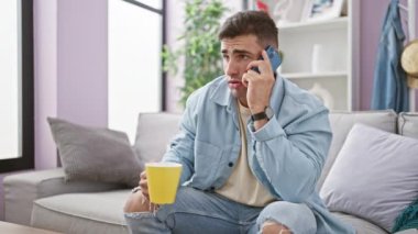 Genç İspanyol adam akıllı telefonda konuşuyor. Evde kahve içiyor.