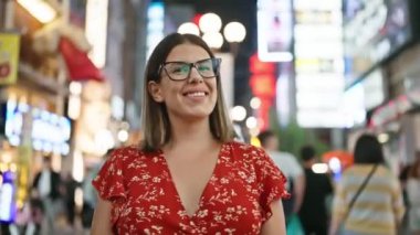 Kendinden emin ve kaygısız, gözlüklü güzel bir İspanyol kadın Osaka 'nın ünlü dotonbori sokağının tadını çıkarıyor. Gülümsüyor, dolup taşan geceye bakıyor, neşe saçıyor..