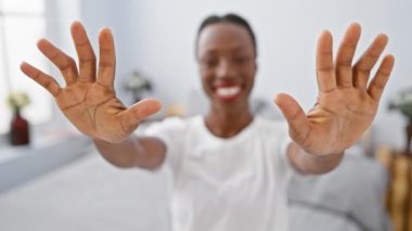 Neşeli Afrikalı Amerikalı kadın yatak odasında dinleniyor, parmaklarıyla 10 numarayı gösteriyor, güzel bir gülümsemeyle işaret ediyor..