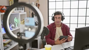Büyüleyici canlı yayın, genç, çekici İspanyol adam, usta radyo muhabiri canlı müzik stüdyosundan haberleri iletiyor, mikrofon elinde.
