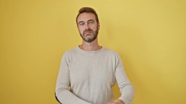 Gülümseyen İspanyol adam güven gösteriyor, kollarını kavuşturuyor ve sarı izole arka planda pozitif düşünüyor.