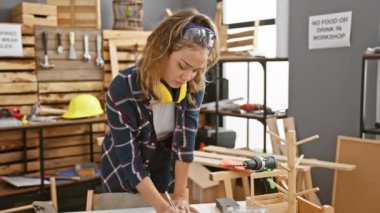 Tüh! Marangozluk stüdyosundaki genç, güzel İspanyol kadın hatayı fark ediyor. Sinirli bir şekilde, unutkan bir şekilde alnına vuruyor. Güvenlik gözlükleri ve kulaklıkları takılı; pişmanlık odayı dolduruyor.