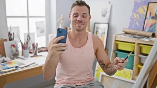 Homme Tatoué Dans Débardeur Prend Selfie Dans Studio Rempli Art — Video