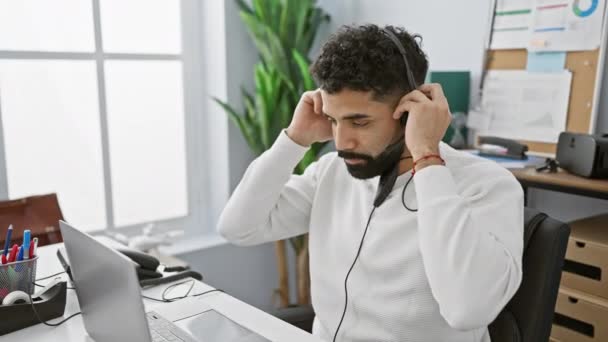 Egy Fiatal Szakállas Férfi Fejhallgatót Visel Problémásnak Tűnik Miközben Laptopjánál — Stock videók