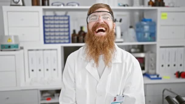 若い赤毛科学者 自信に満ちた笑顔 ラボで安全な眼鏡をスポーツする男 — ストック動画