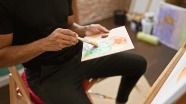 Parlak bir stüdyoda tuvale resim yapan, yaratıcılığı ve konsantrasyonu somutlaştıran odaklanmış bir İspanyol..