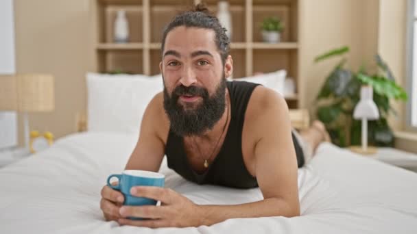 一个快乐的满脸胡须的男人在阳光灿烂的卧室里喝咖啡 流露出舒适的生活方式 — 图库视频影像