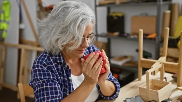 Starší Žena Usrkává Kávu Dřevoobráběcím Studiu Obklopená Nástroji Dřevěnými Řemesly — Stock video