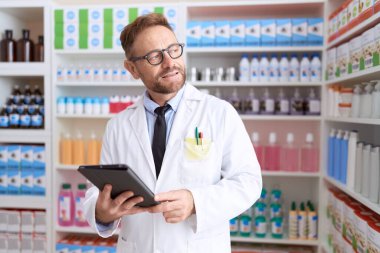 Middle age man pharmacist using touchpad working at pharmacy