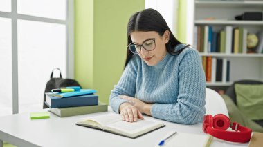 Kütüphane Üniversitesi 'nde kitap okuyan genç İspanyol kadın öğrenci.