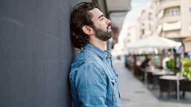 Duvara yaslanan genç bir İspanyol sokakta stresli.