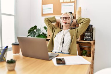 Genç sarışın kadın iş adamı ajan. Elleri ofiste dinleniyor.