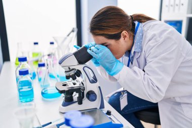 Laboratuvarda mikroskop kullanan genç ve güzel İspanyol bilim kadını.