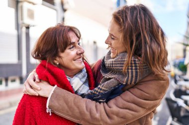 İki kadın anne ve kızı sokakta birbirlerine sarılıyorlar.