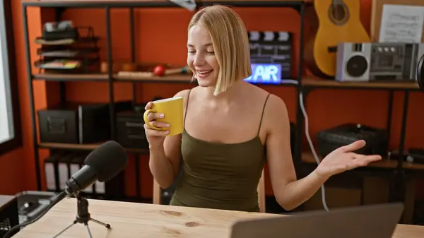 Young blonde woman radio reporter drinking coffee speaking at podcast studio