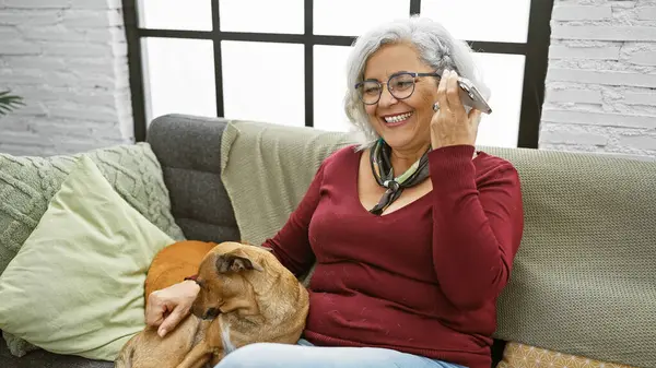 Gülümseyen Bir Kadın Evde Rahat Bir Kanepede Köpeğini Kucaklayan Bir — Stok fotoğraf