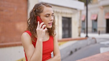 Çekici genç bir kadın ciddi bir telefon konuşmasına daldı. İfadesi kalabalık bir şehir caddesine karşıydı.