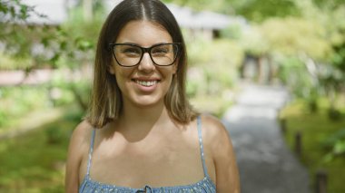 Gözlüklü güzel İspanyol kadın, gülümseyişinin neşeli portresi, gülüşü ve japan 'ın geleneksel Kyoto parkında kendine güvenen pozu, tasasız yüzünde doğayla çevrili duygular.