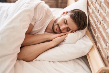 Genç beyaz adam yatakta uzanıyor. Yatak odasında uyuyor.