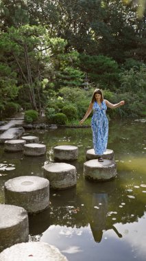 Güzel İspanyol kadının sakin yaz yürüyüşü taştan yol boyunca geleneksel Heian Jingu Tapınağı 'nda bir gölden geçiyor.