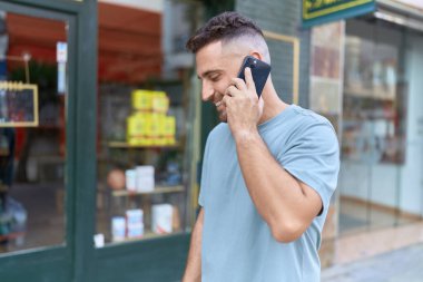 Genç İspanyol adam gülümsüyor. Kendine güveniyor. Sokakta akıllı telefondan konuşuyor.