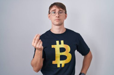 Beyaz, sarışın, bitcoin tişörtlü, italyan jestleri yapan, kendine güvenen bir adam. 