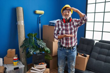 Neşeli kıdemli adam, yeni ev güvenliği önlemleri için büyük ölçekli bir sembol olan elleriyle büyük ölçekli jest yapıyor. Spor şapkalı ve gözlüklü, bu adam gülümsüyor.!