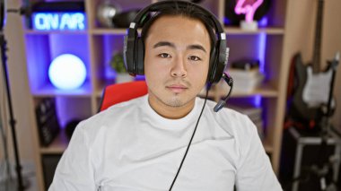 Yoğun bir gece akışı, genç Çinli bir adam, ciddi bakışları olan, oyun odasına bağlanmış, kulaklık hazır, fütüristik siber eğlenceye dalmış