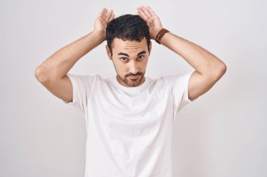 Beyaz arka planda duran yakışıklı İspanyol bir adam. Tavşan kulağı hareketi yapıyor. Avuçlarıyla alaycı ve şüpheci görünüyor. Paskalya tavşanı konsepti. 