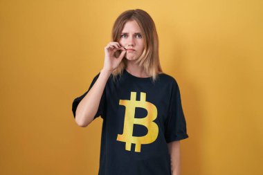 Sarışın, beyaz kadın bitcoin tişört giyiyor. Ağzı ve dudakları parmakları fermuar gibi kapalı. gizli ve sessiz, tabu konuşması 