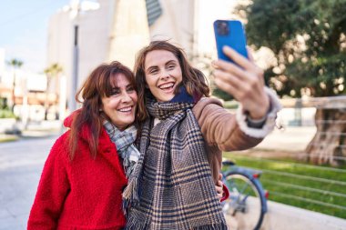 Two women mother and daughter make selfie by smartphone at park