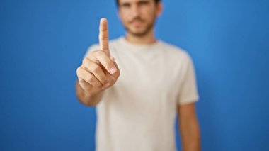 Sakallı yakışıklı İspanyol adam mavi arka planı işaret ediyor.