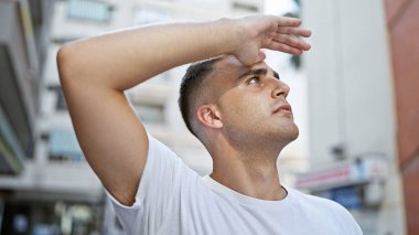 Yakışıklı, genç, İspanyol bir adam şehir sokaklarında güneşten korunuyor..