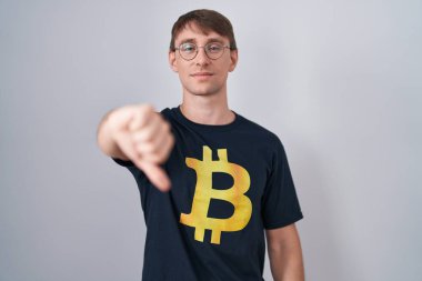 Bitcoin tişört giyen, beyaz tenli, sarışın, mutsuz görünen, reddedilmiş ve olumsuz davranan bir adam. kötü ifade. 
