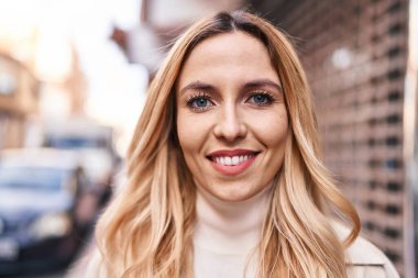 Sokakta kendine güvenen genç sarışın kadın gülümsüyor