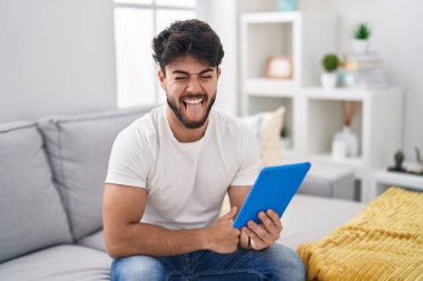 Sakallı İspanyol bir adam kanepeye oturmuş komik bir ifadeyle dilini dışarı çıkartıyor. duygu kavramı. 