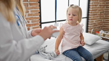 Mahallenin kliniğinde yapılan kritik sağlık kontrolünde ilgilenen doktor ve cesur küçük hasta yakınlaşması.