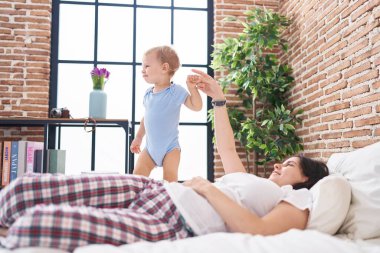 Anne ve oğlu yatakta uzanıp yatak odasında oynuyorlar.